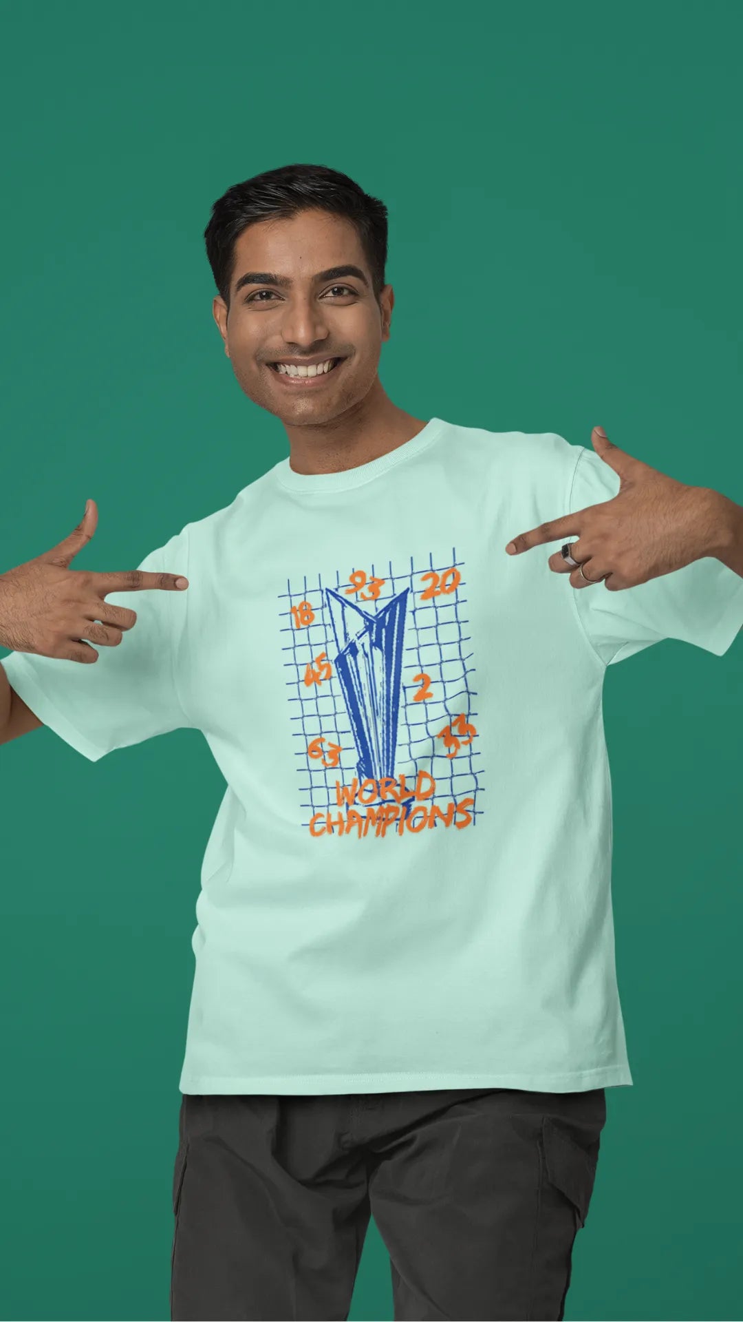 Third front image of male model wearing a mint green oversized t-shirt featuring the World Cup 2024 trophy with the text "World Champions" underneath. Ideal for Indian cricket fans celebrating their team's victory.