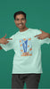 Third front image of male model wearing a mint green oversized t-shirt featuring the World Cup 2024 trophy with the text 