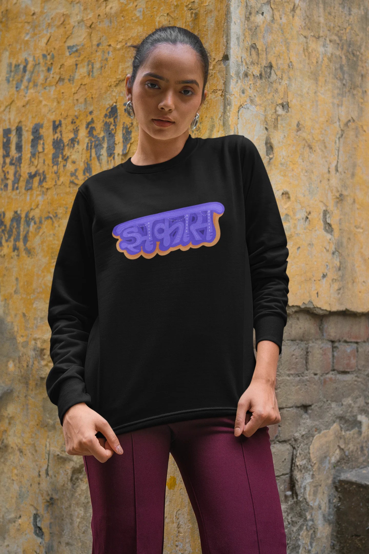 3rd front view of a female model wearing an black sweatshirt featuring "Jhakas" in a stylish font.