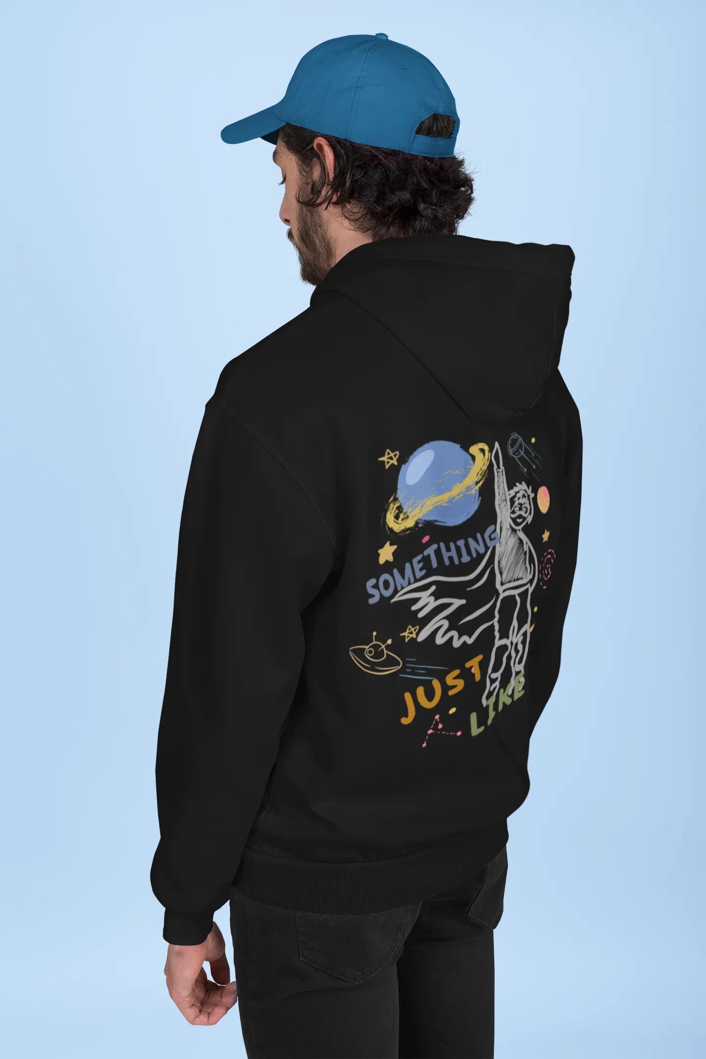 Back view of a male model wearing an black hoodie with a design inspired by the "Something Just Like This" music video, featuring the word "Superheroes".