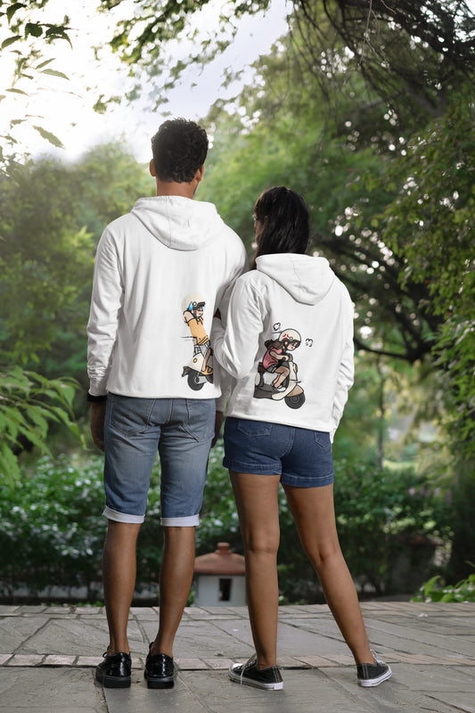 Back view of a couple wearing matching hoodies with a split design. The left side shows a guy relaxing in the backseat of a scooter, while the right side shows his girlfriend driving off.