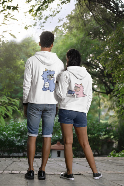 Back view of a couple wearing matching cream hoodies, one with Tom the cat and the other with Jerry the mouse, both dressed in dinosaur costumes.