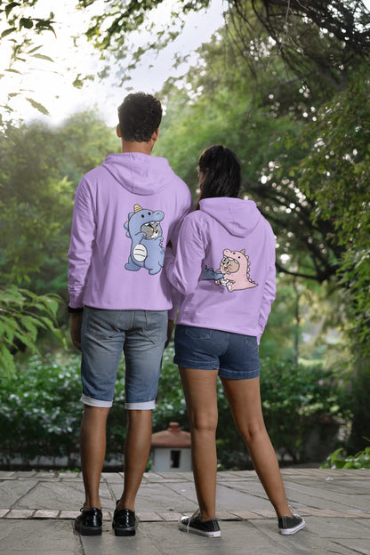 Back view of a couple wearing matching lavender hoodies, one with Tom the cat and the other with Jerry the mouse, both dressed in dinosaur costumes.