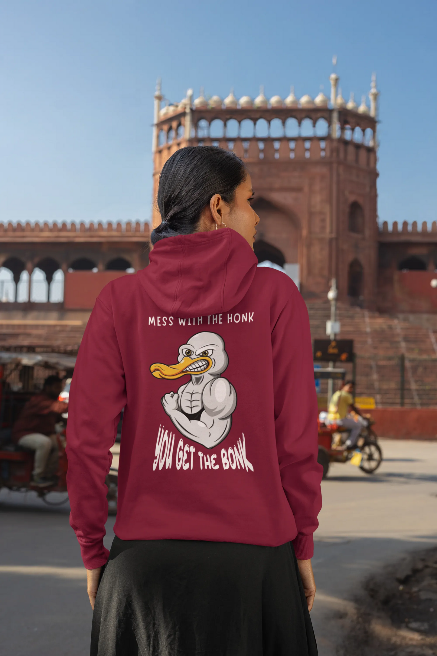 Back view of a female model wearing a maroon hoodie with a Disney design featuring a muscular duck and the text "The Honk."