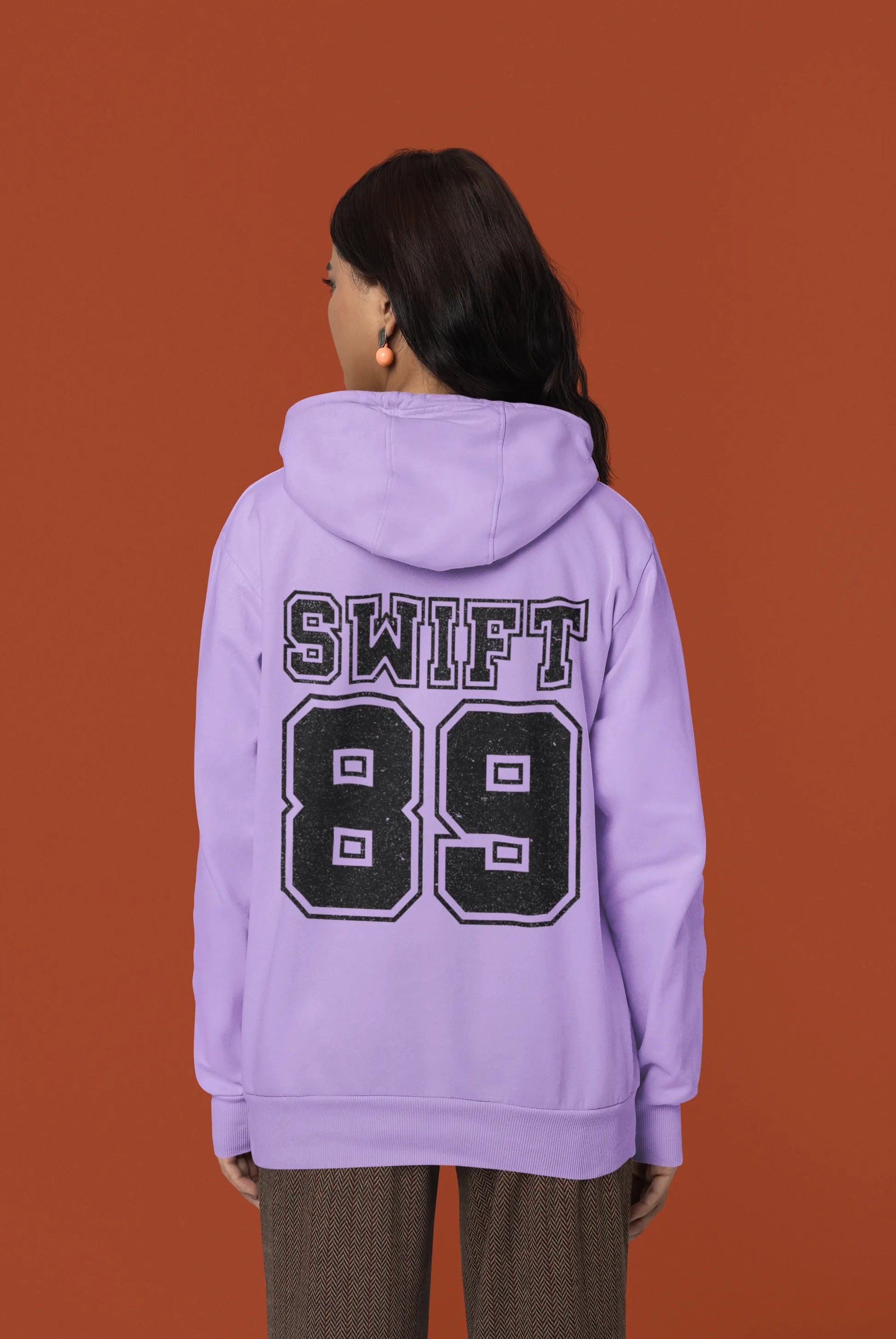 Back view of a female Model wearing a lavender Swift 89 hoodie, inspired by Taylor Swift's 1989 album. Perfect for Swifties and Eras Tour fans.