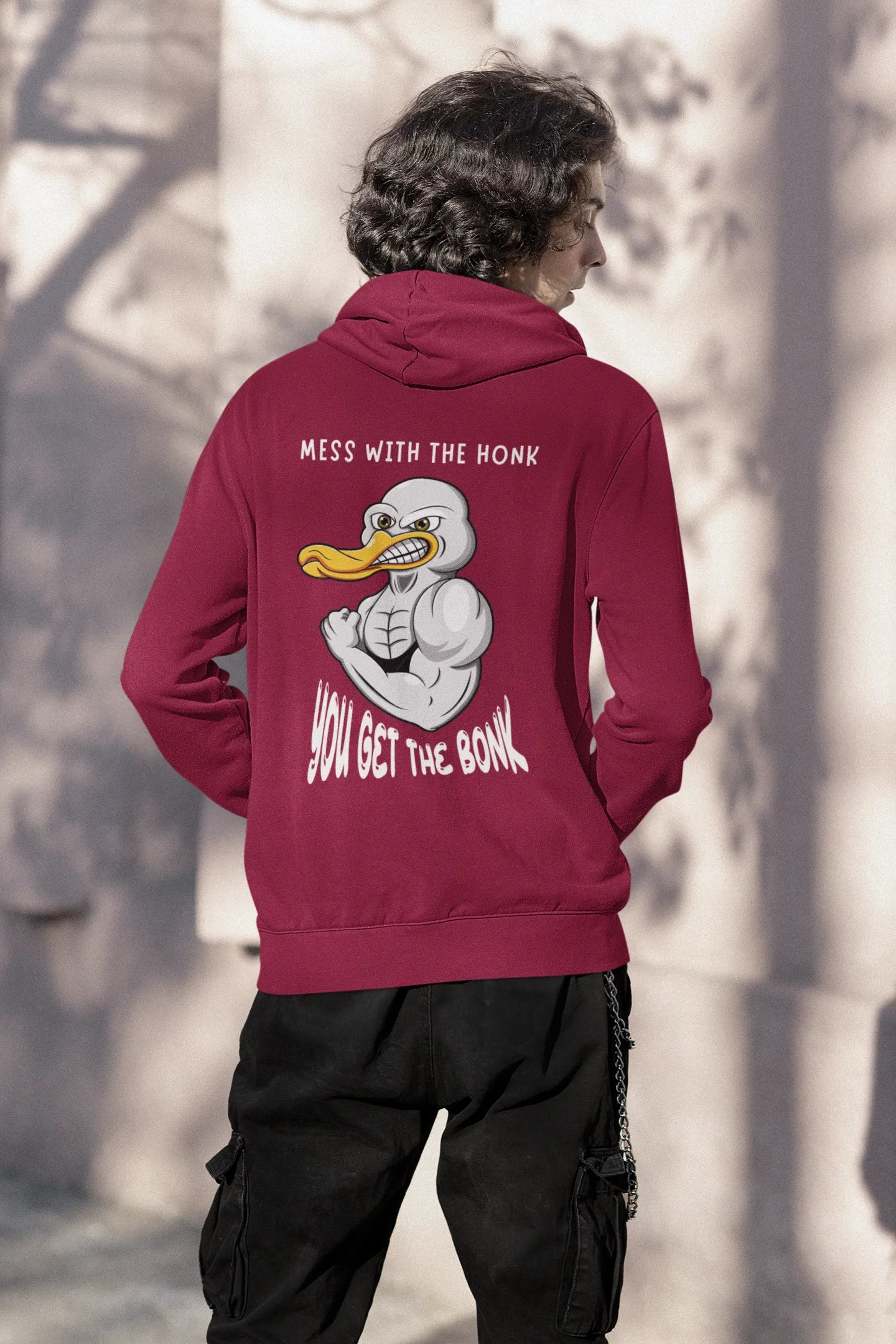 Back view of a male model wearing a maroon hoodie with a Disney design featuring a muscular duck and the text "The Honk."