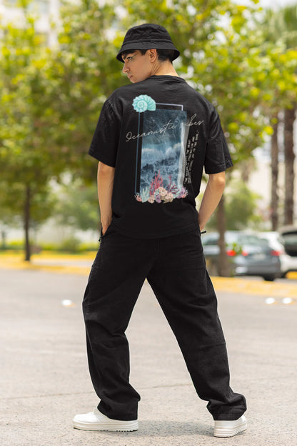 Back view of a male model wearing a black Oversized t-shirt featuring a stunning design of corals and shells, evoking a serene underwater atmosphere.