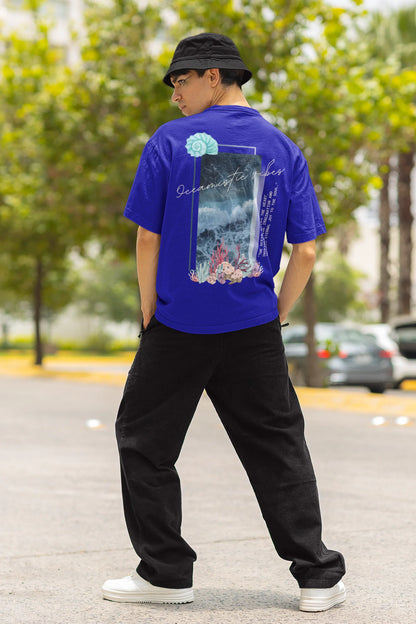 Back view of a male model wearing a royal blue Oversized t-shirt featuring a stunning design of corals and shells, evoking a serene underwater atmosphere.