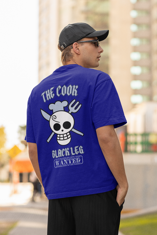 Back view of a male model wearing a royal blue oversized t-shirt featuring Sanji's skull and crossbones logo and the text "The Cook and Black Leg."
