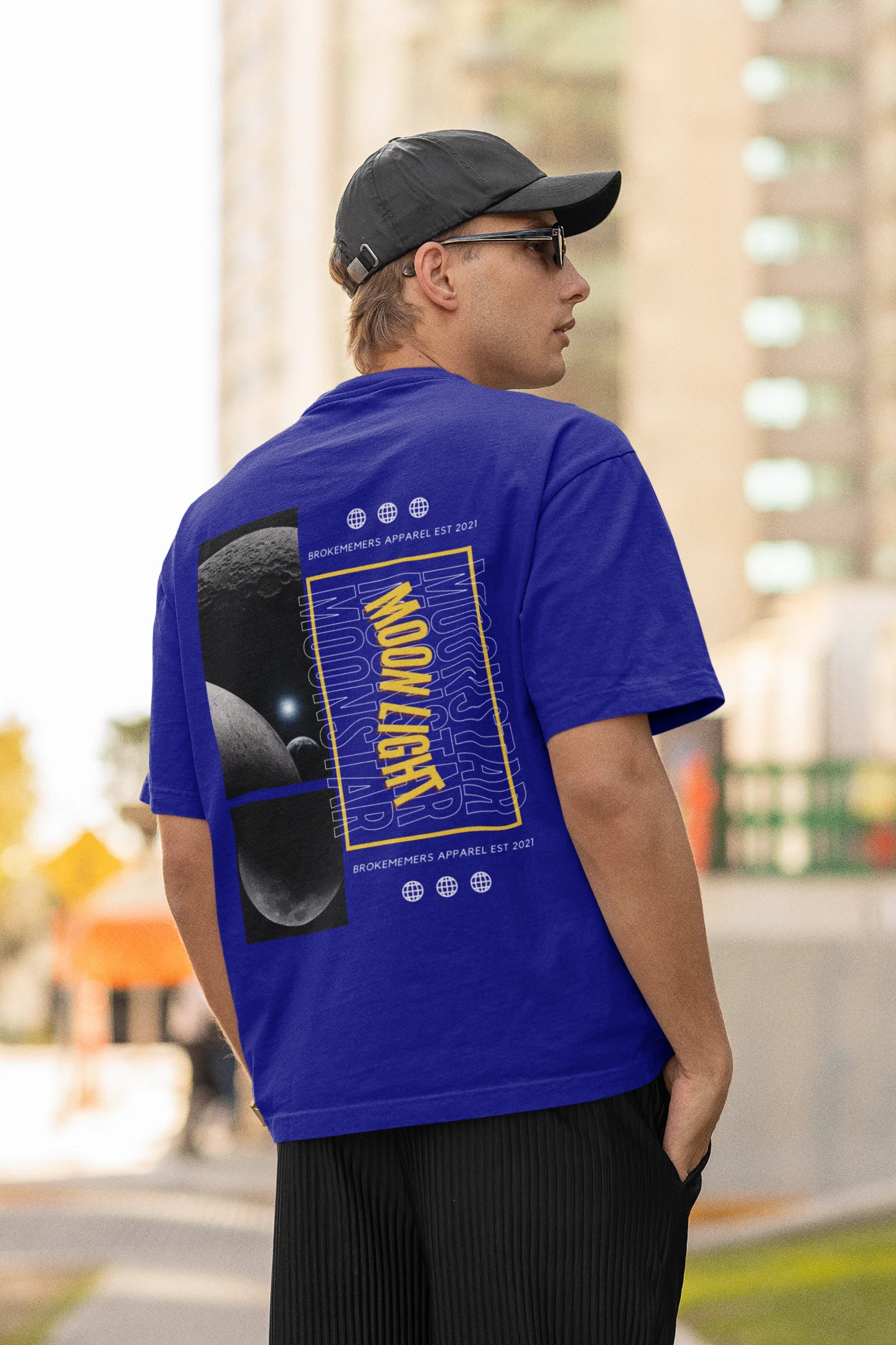 Back view of male model wearing a royal blue oversized t-shirt featuring a captivating "moonlight" design with subtle elements of the Milky Way galaxy, planets, and the soft glow of the moon.