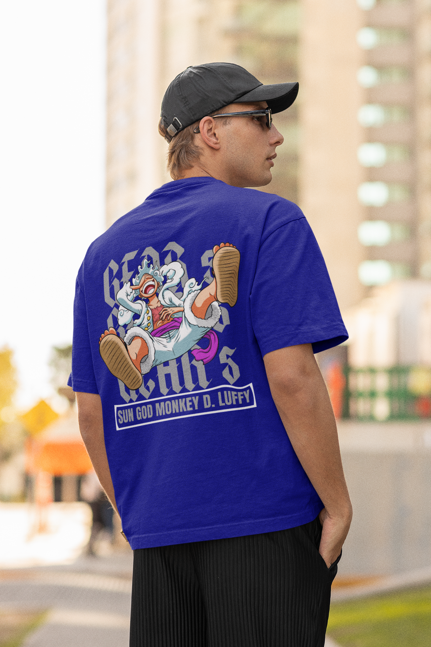 Back view of a male model wearing a royal blue oversized t-shirt featuring Luffy in his Gear 5 form from the One Piece anime.