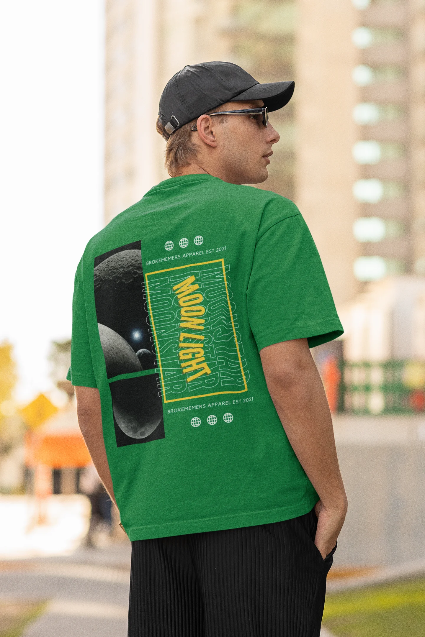 Back view of male model wearing a forest green oversized t-shirt featuring a captivating "moonlight" design with subtle elements of the Milky Way galaxy, planets, and the soft glow of the moon.