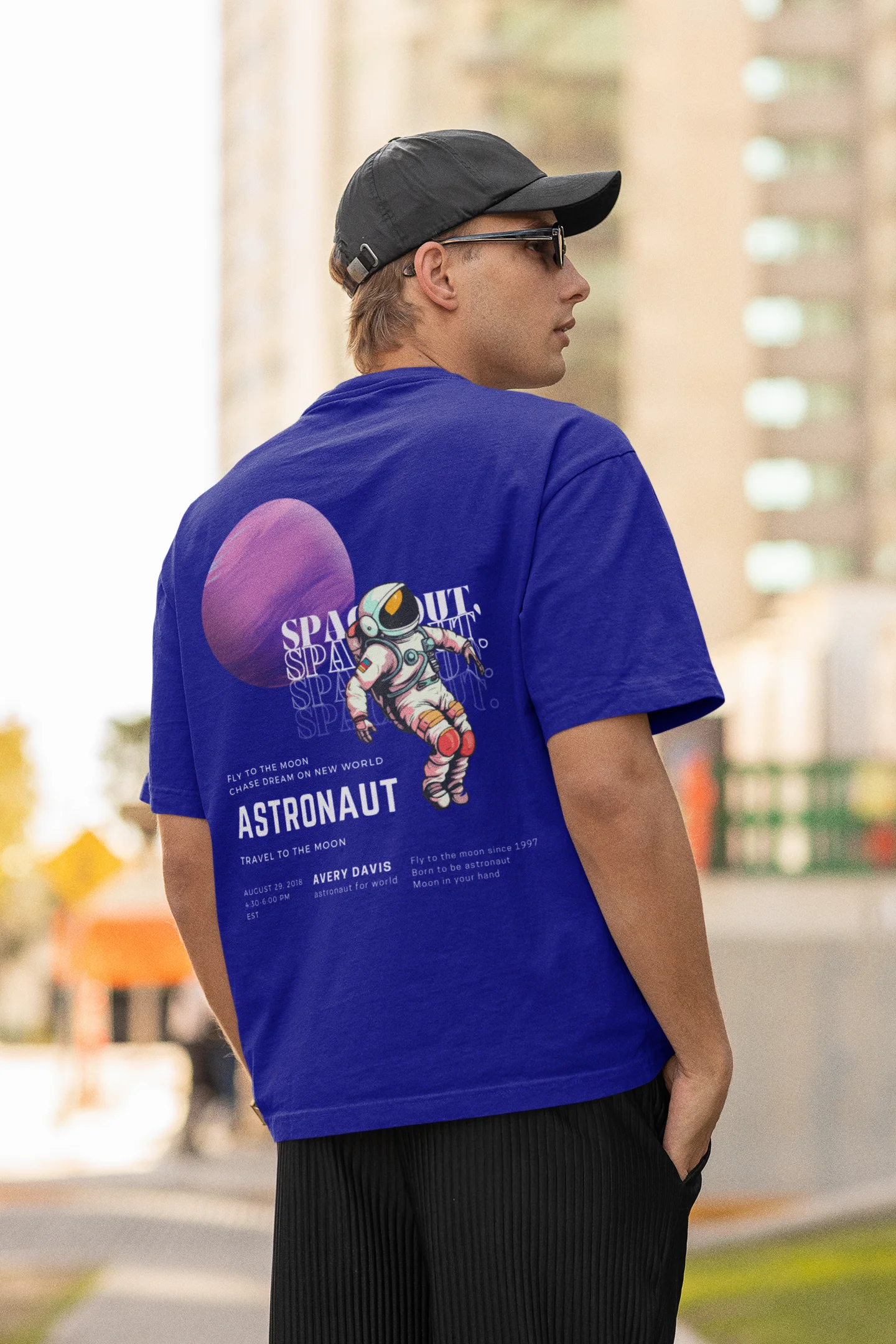 Back view of male model wearing a blue oversized t-shirt featuring a design inspired by the cosmos and galaxies "Fly Me to the Moon" and subtle hints of space exploration.