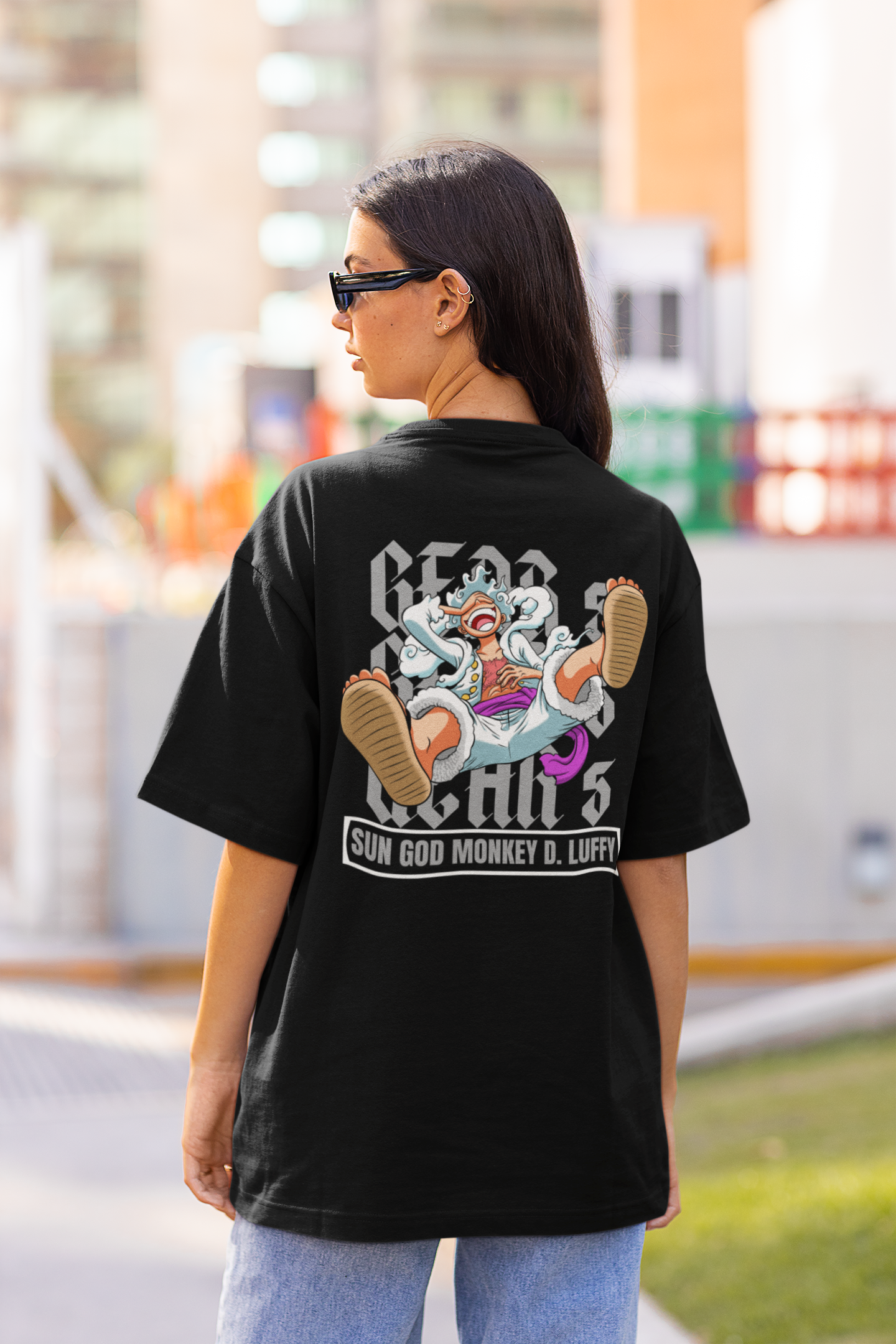 Back view of a female model wearing a black oversized t-shirt featuring Luffy in his Gear 5 form from the One Piece anime.