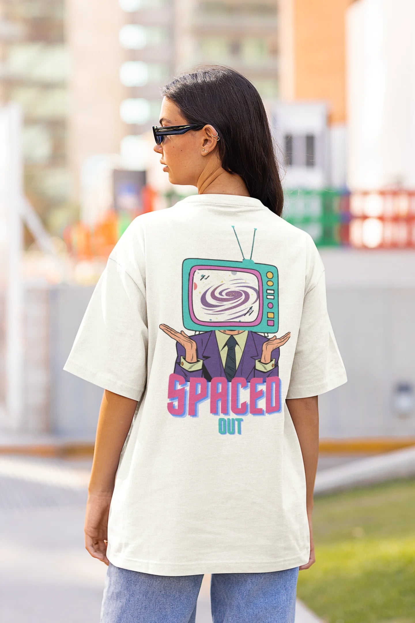Back view of a female model wearing a white oversized t-shirt with a bold graphic that reads "Need Some Space" on the front. The design incorporates subtle hints of the Milky Way galaxy and the solar system on the back.