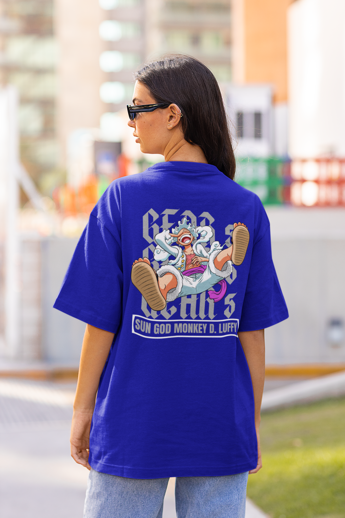Back view of a female model wearing a royal blue oversized t-shirt featuring Luffy in his Gear 5 form from the One Piece anime.