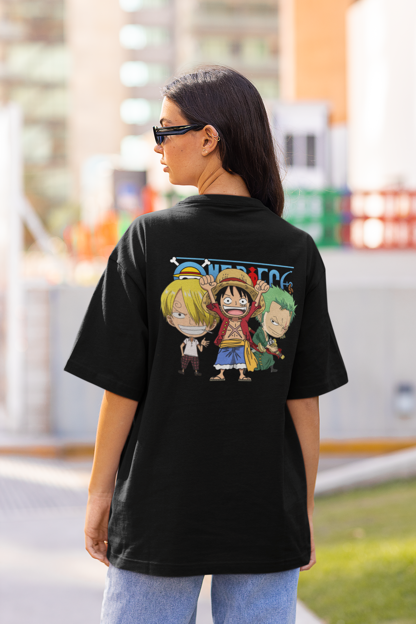 Back view of a female model wearing a black oversized t-shirt featuring chibi versions of the main characters from the One Piece anime.