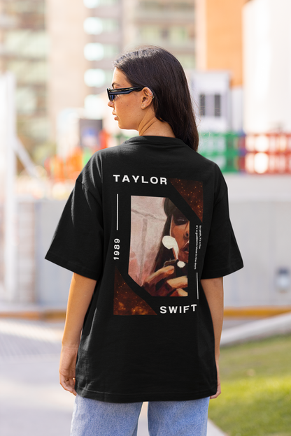 Back view of woman wearing black coloured Oversize T-shirt featuring Taylor Swift 1989 design, Taylor's Version, and Eras Tour Merch