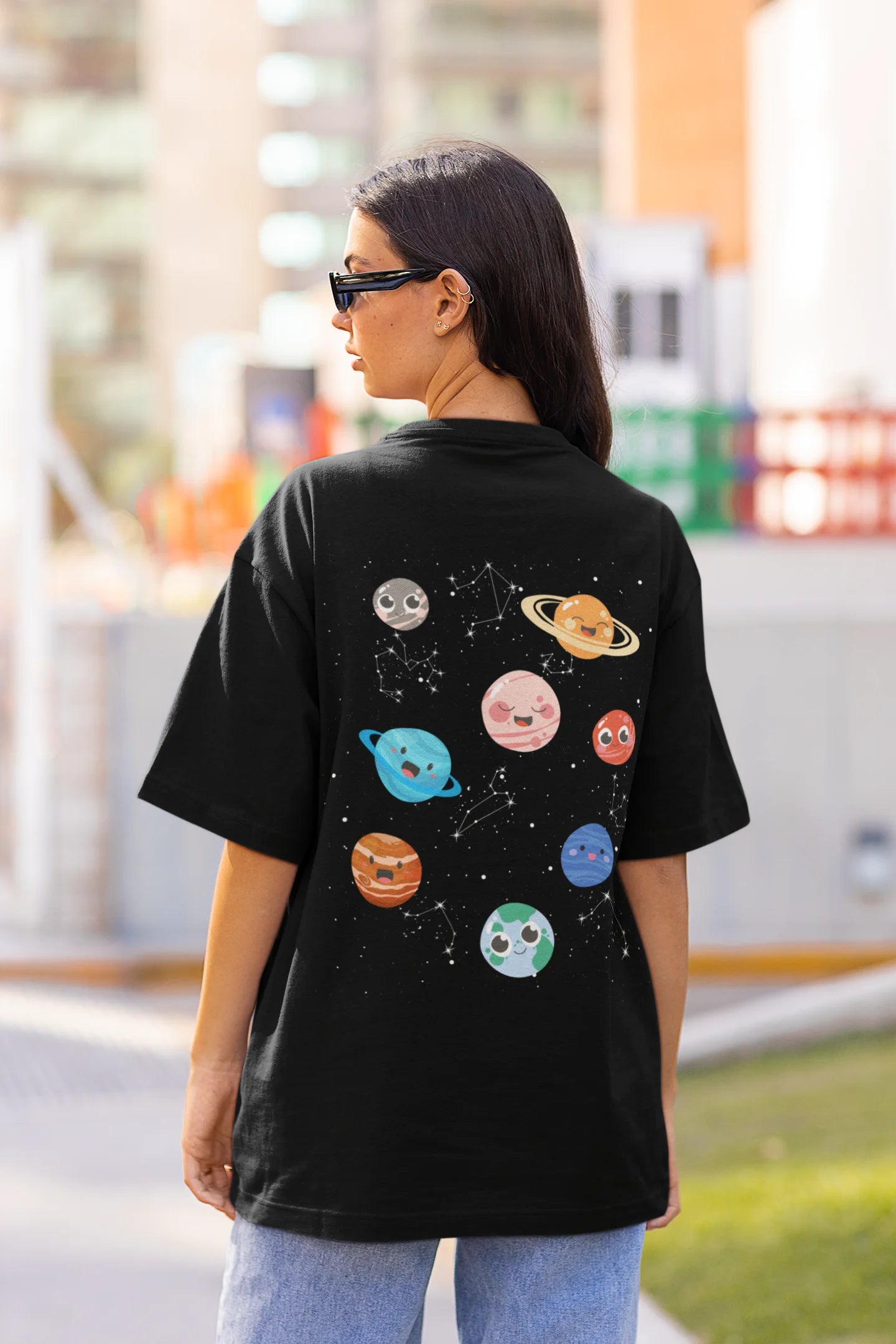 Back view of female model wearing an black oversized t-shirt featuring a colorful "Solar System" design with all eight planets.
