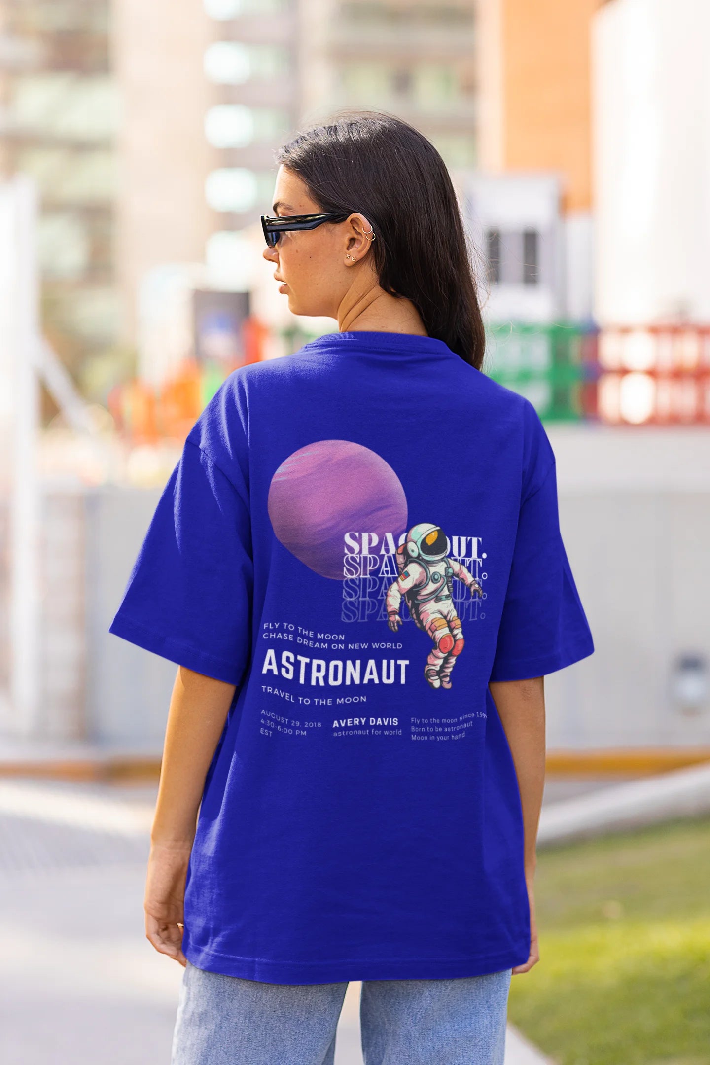 Back view of female model wearing a blue oversized t-shirt featuring a design inspired by the cosmos and galaxies "Fly Me to the Moon" and subtle hints of space exploration.