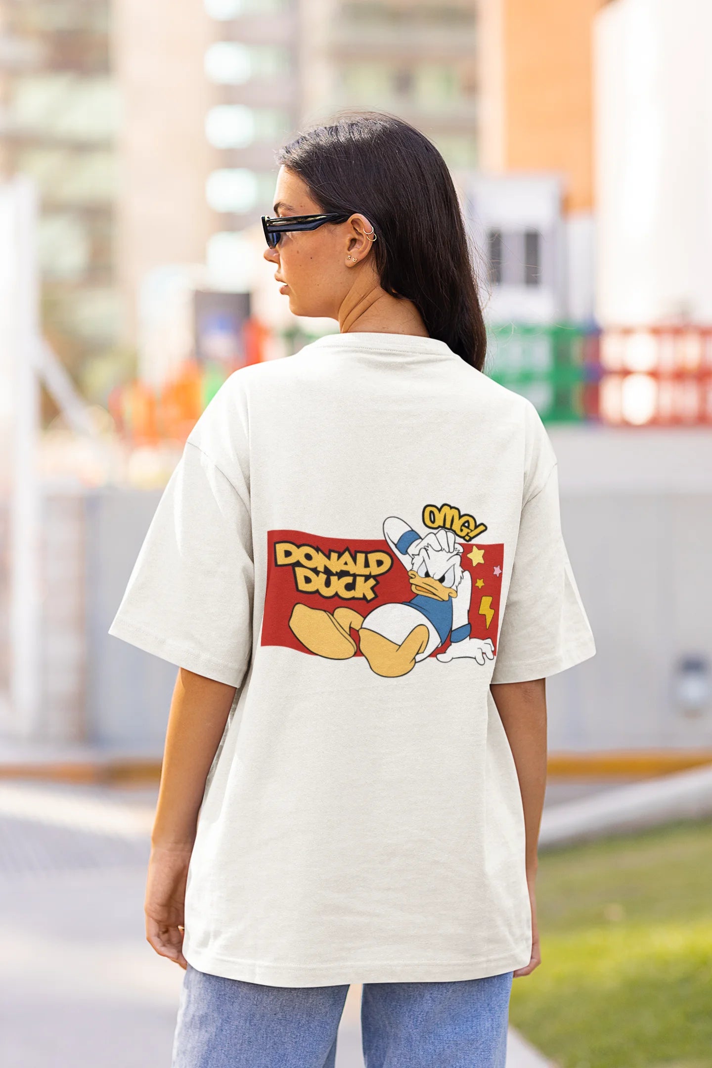 Back view of female model wearing off white oversized Disney collection t-shirt featuring a classic Donald Duck design.