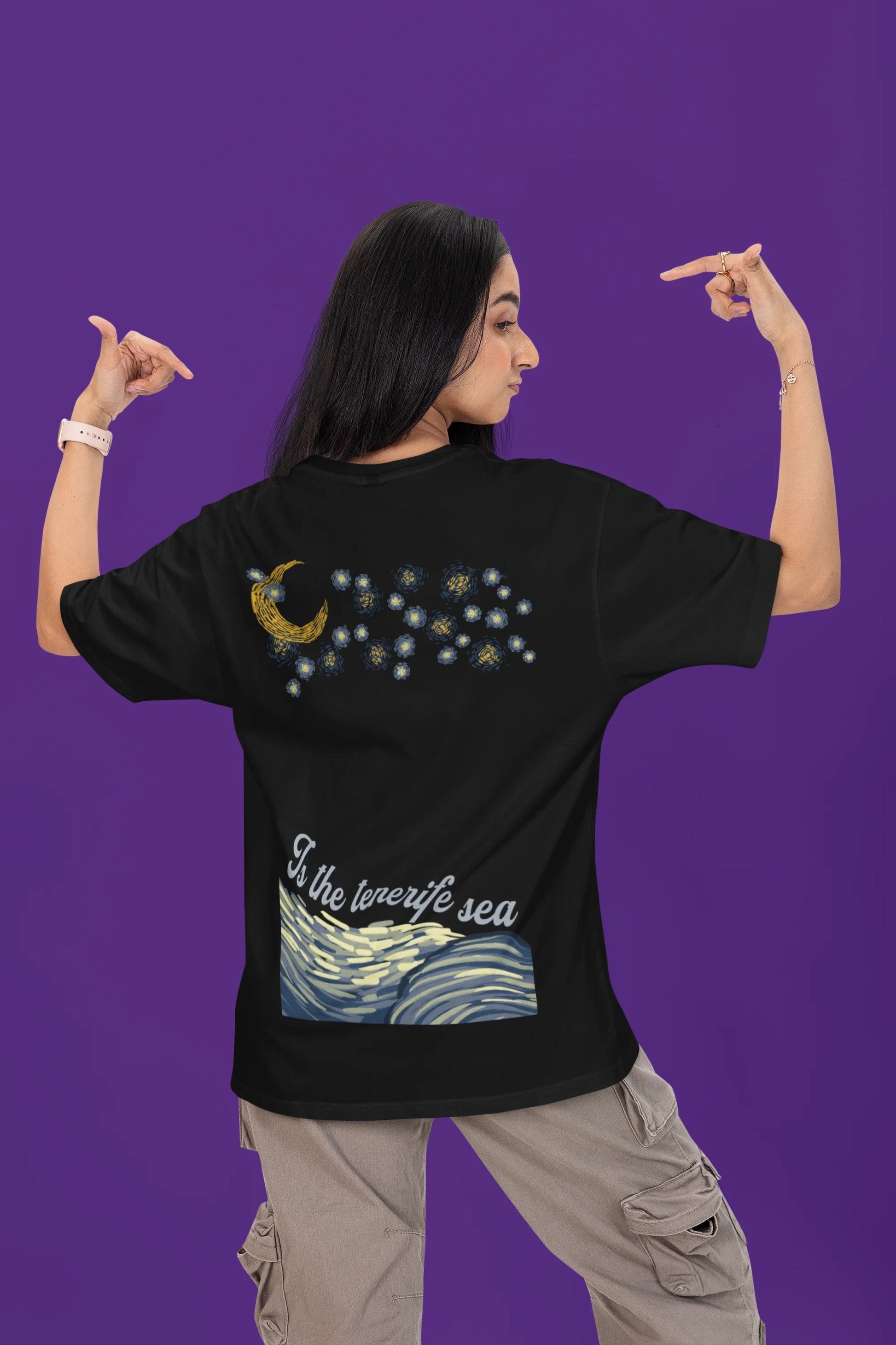 Back view of a female model wearing a black oversized t-shirt featuring a beach at night with a starry sky above, inspired by Ed Sheeran's "Tenerife Sea."