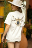 Back view of female model wearing an off-white oversized t-shirt featuring a thought-provoking design of a golden lock shaped like an insect. Ideal for those who love symbolic clothing and unique conversation starters.