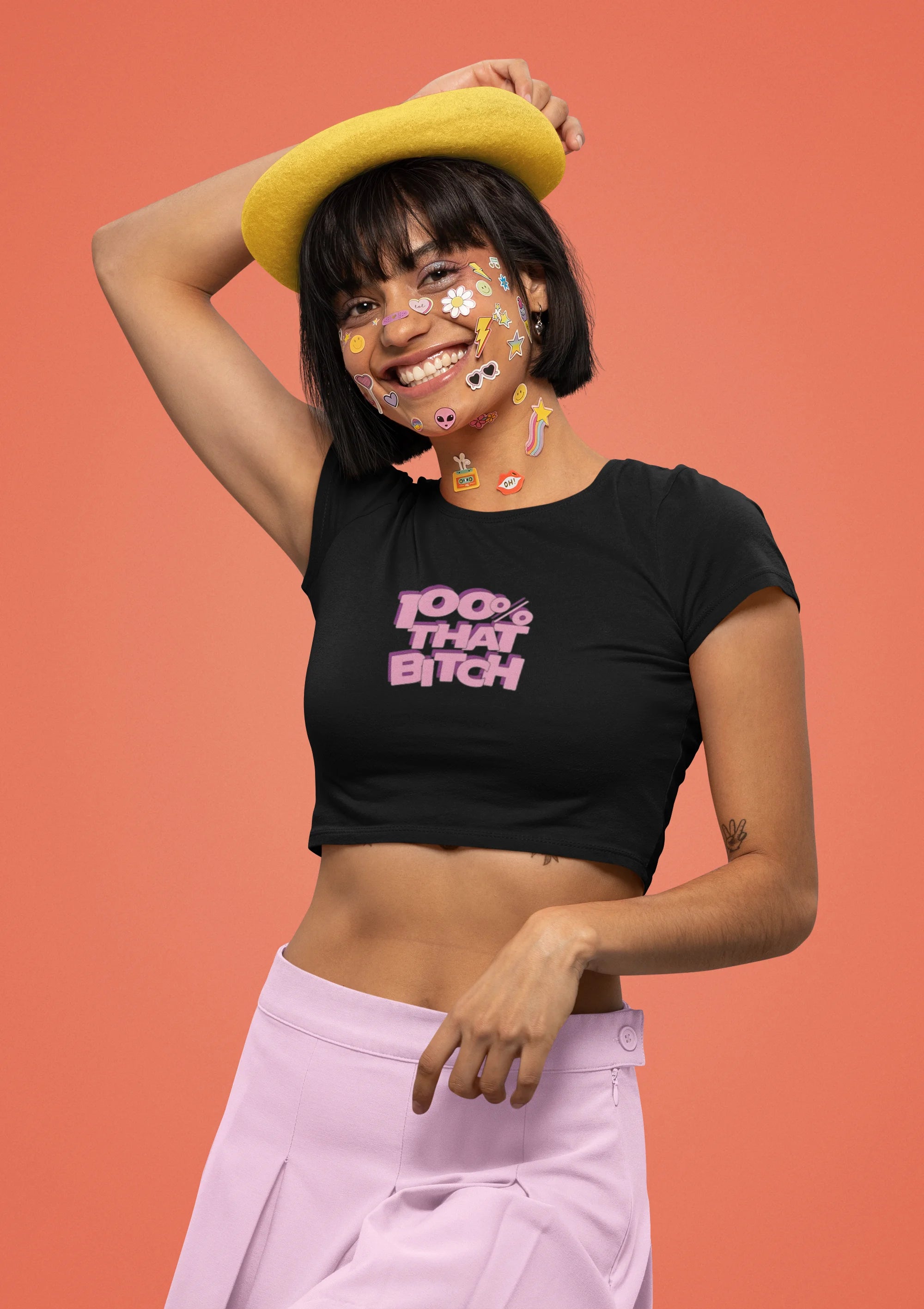 First front view of female model wearing a stylish black crop top with a bold 100% that bitch design, exuding confidence and attitude.