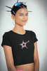 Side view of a female model wearing a black crop top with a shooting star (Starblink) design, radiating confidence and style.