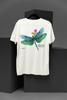 Back view of an off-white oversized t-shirt featuring a nature-inspired design with a blue dragonfly perched on flowers amidst green grass. Ideal for those who love springtime aesthetics and dragonfly imagery.