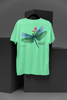 Back view of a mint green oversized t-shirt featuring a nature-inspired design with a blue dragonfly perched on flowers amidst green grass. Ideal for those who love springtime aesthetics and dragonfly imagery.