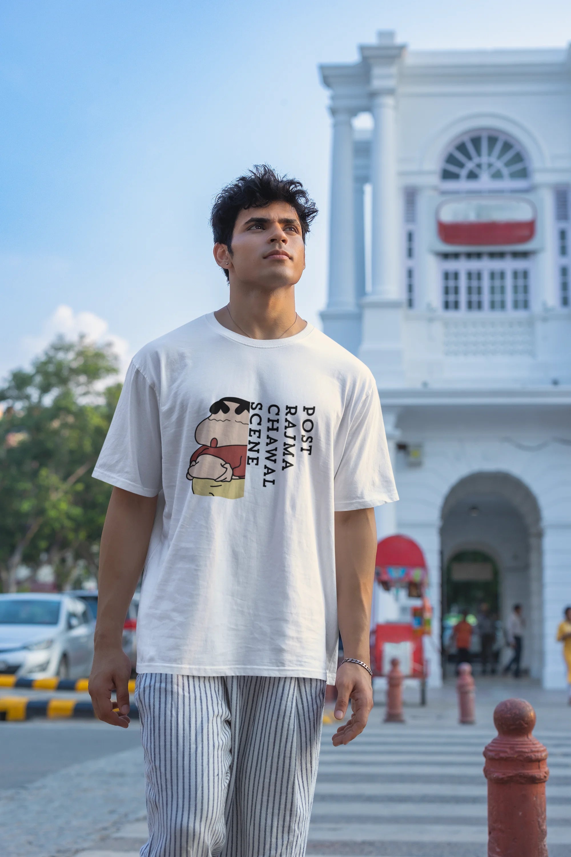 Third front image of male model wearing an oversized off-white tee with a humorous design of Shinchan enjoying a food coma. A must-have for Shinchan fans and food lovers.