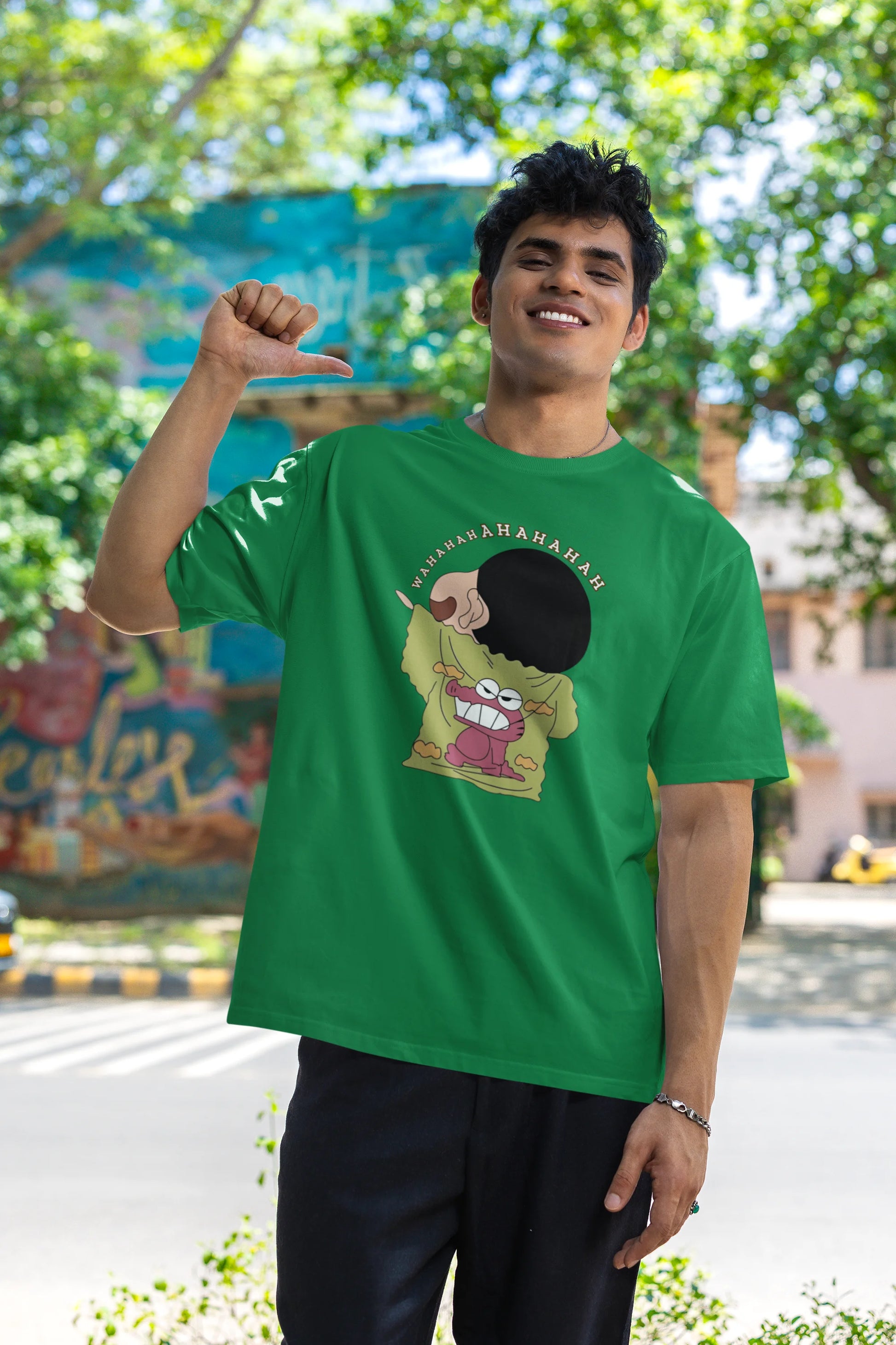 Third front view of male model wearing a forest green oversized t-shirt with a design of Shinchan laughing hysterically. Perfect for Shinchan fans who love the character's humor.