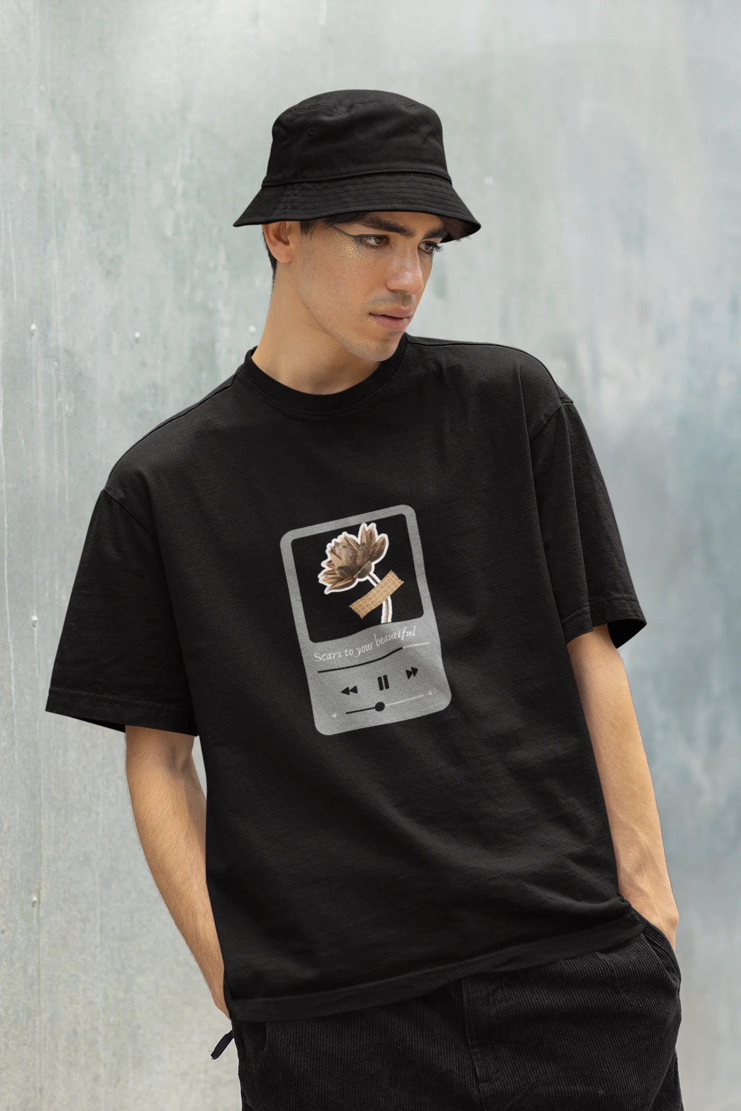 Front view of a male model wearing a black oversized t-shirt featuring a design inspired by Alessia Cara's song "Scars to Your Beautiful." The design includes flowers and a message of self-love. Ideal for fans of Alessia Cara and those who appreciate messages of empowerment.