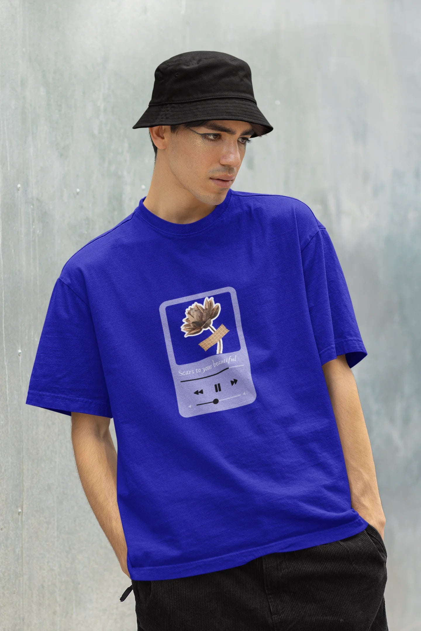 Front view of a male model wearing a royal blue oversized t-shirt featuring a design inspired by Alessia Cara's song "Scars to Your Beautiful." The design includes flowers and a message of self-love. Ideal for fans of Alessia Cara and those who appreciate messages of empowerment.