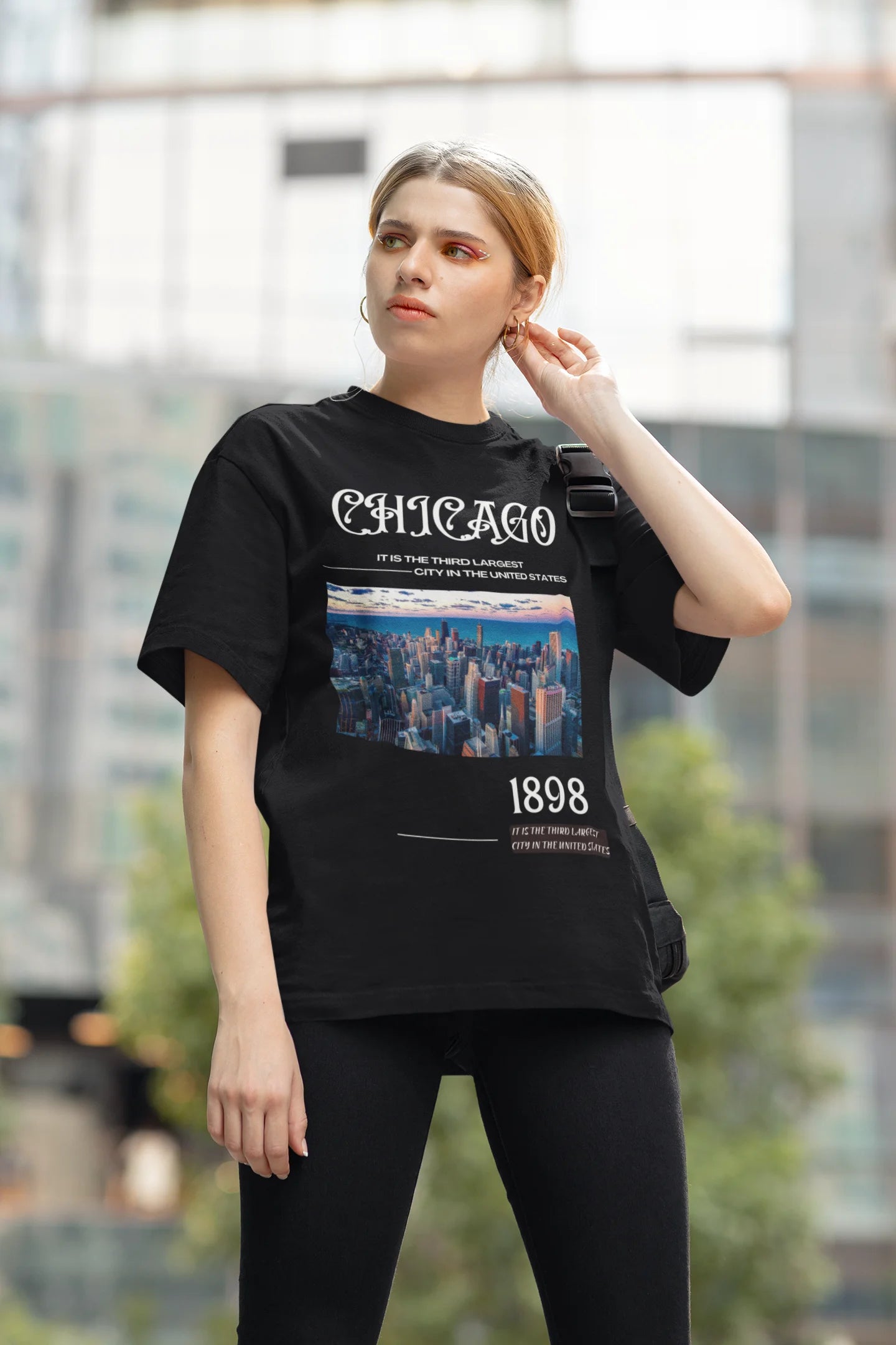 Side view of female model wearing a black oversized t-shirt with a Chicago skyline design, offering a relaxed urban aesthetic.