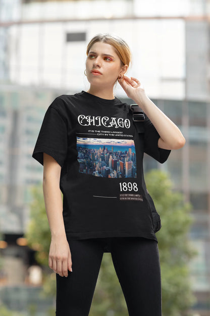 Side view of female model wearing a black oversized t-shirt with a Chicago skyline design, offering a relaxed urban aesthetic.