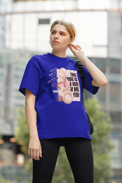 Second front view of a female model wearing an royal blue oversized t-shirt with a heartwarming design of a teddy bear offering a hug, offering a comforting and relaxing aesthetic.