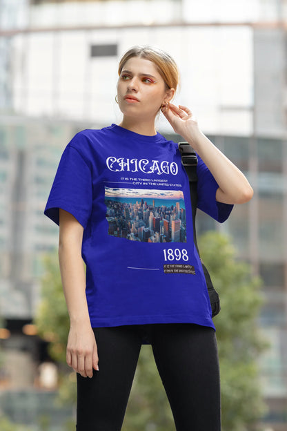 Side view of a female model wearing a royal blue oversized t-shirt with a Chicago skyline design, offering a relaxed urban aesthetic.