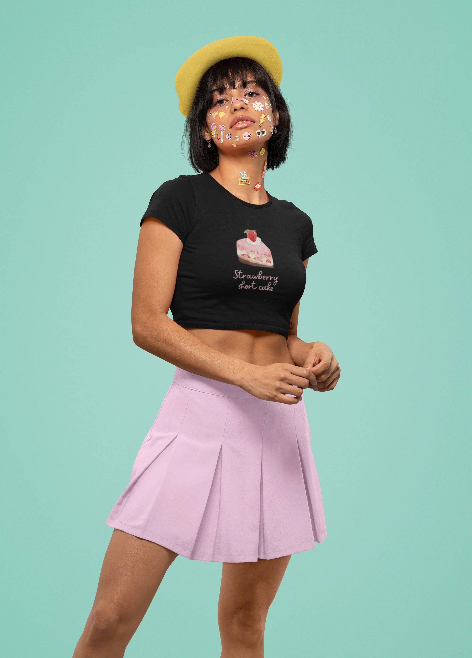 Side view of female a model wearing a stylish black crop top with a playful strawberry shortcake design, exuding confidence and personality.