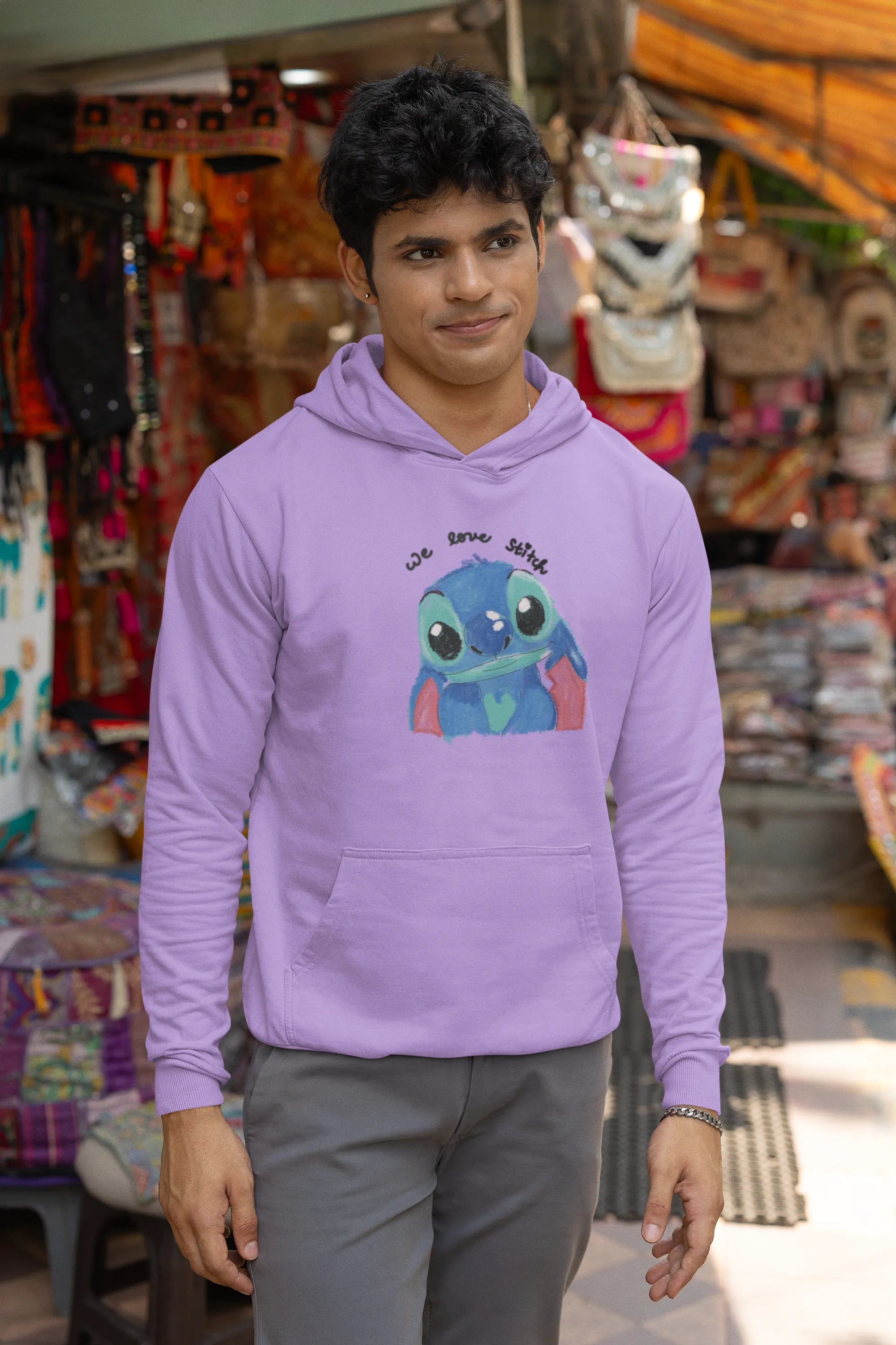 Third front view of a male model wearing a lavender hoodie with a large Stitch design. The illustration shows Stitch smiling and waving.