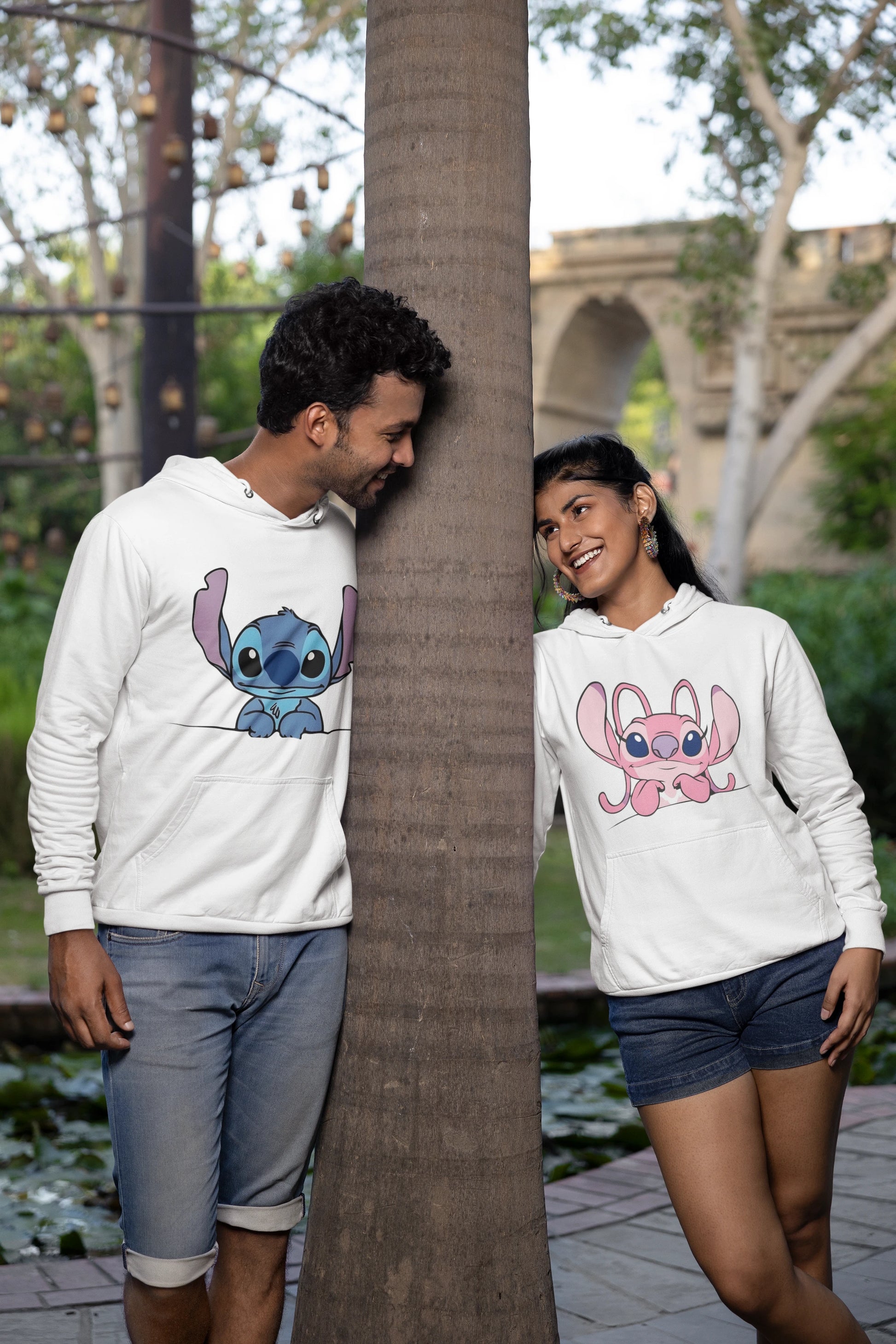3rd front view of a couple wearing matching white hoodies, one with a Stitch design and the other with an Angel design.