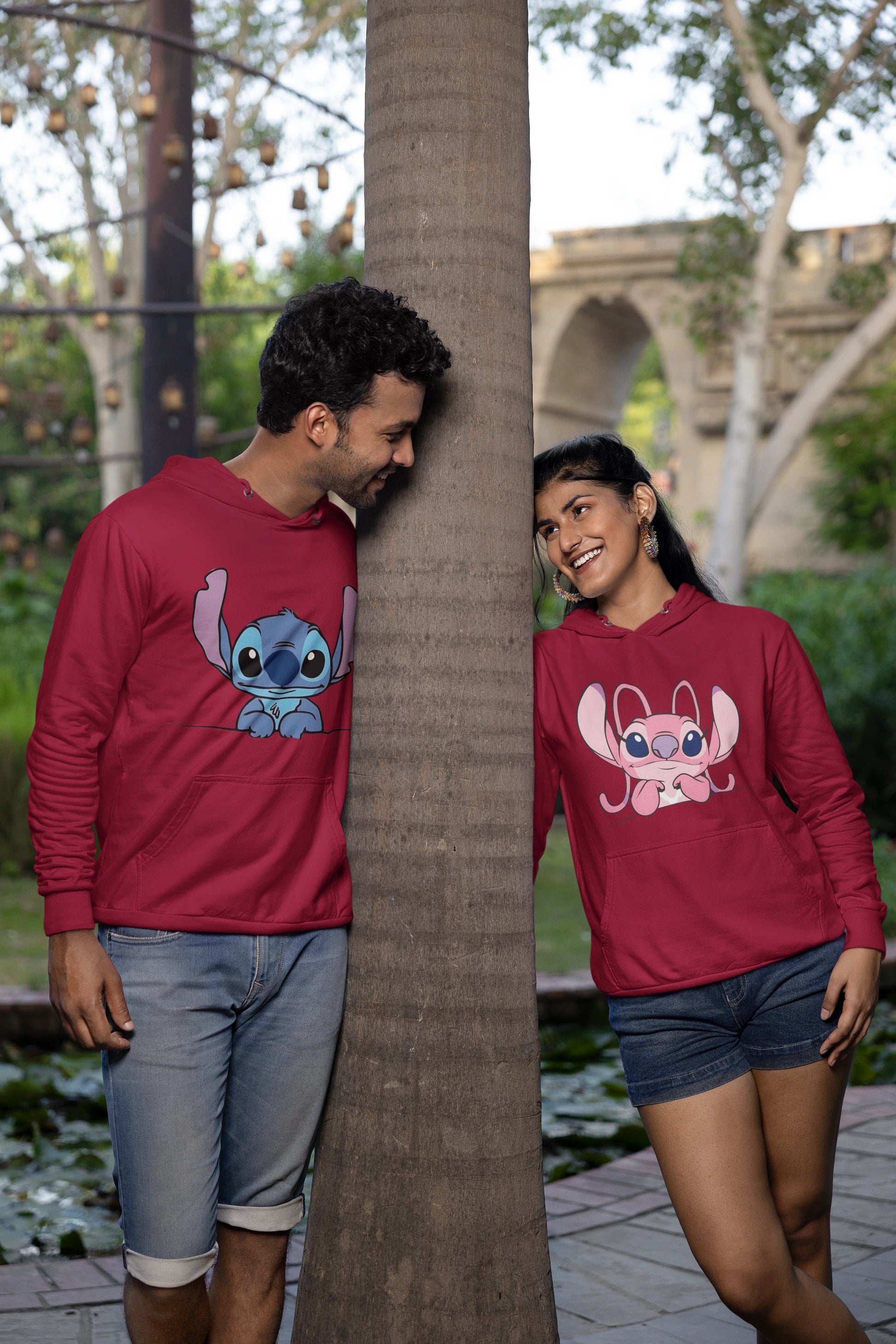 3rd front view of a couple wearing matching maroon hoodies, one with a Stitch design and the other with an Angel design.