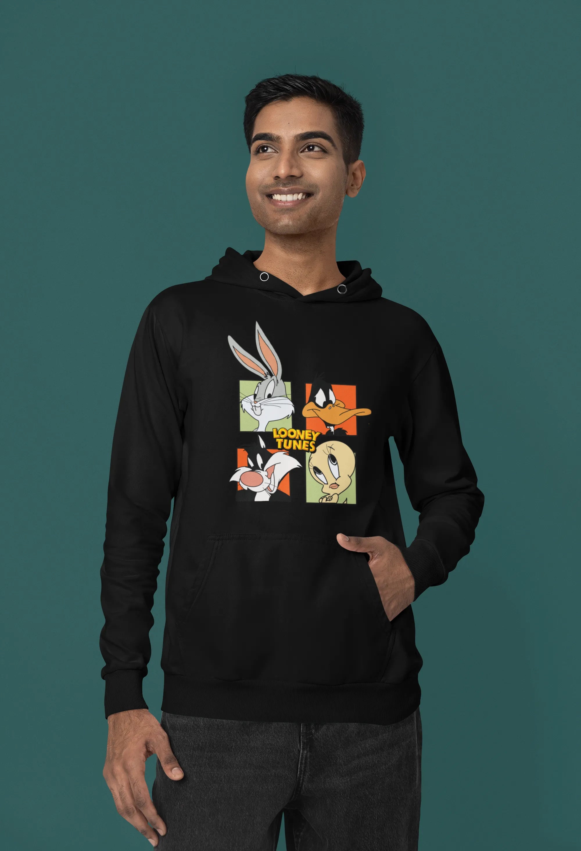 Second image of a male model wearing a black hoodie with a large Looney Tunes design. The illustration features portraits of several iconic Looney Tunes characters.