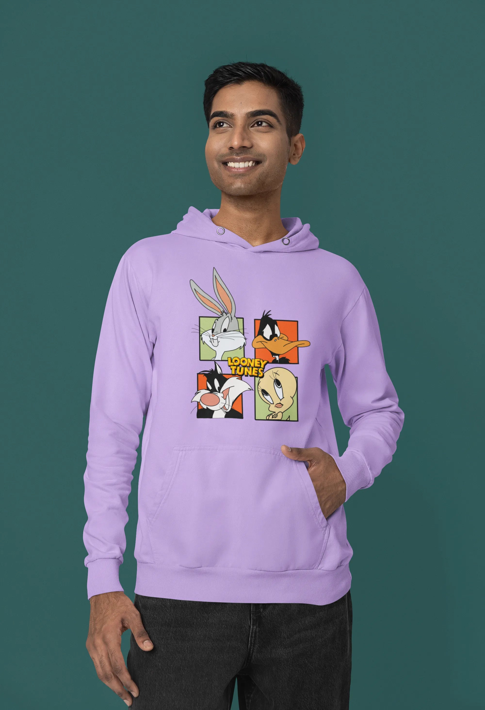 Second image of a male model wearing a lavender hoodie with a large Looney Tunes design. The illustration features portraits of several iconic Looney Tunes characters.