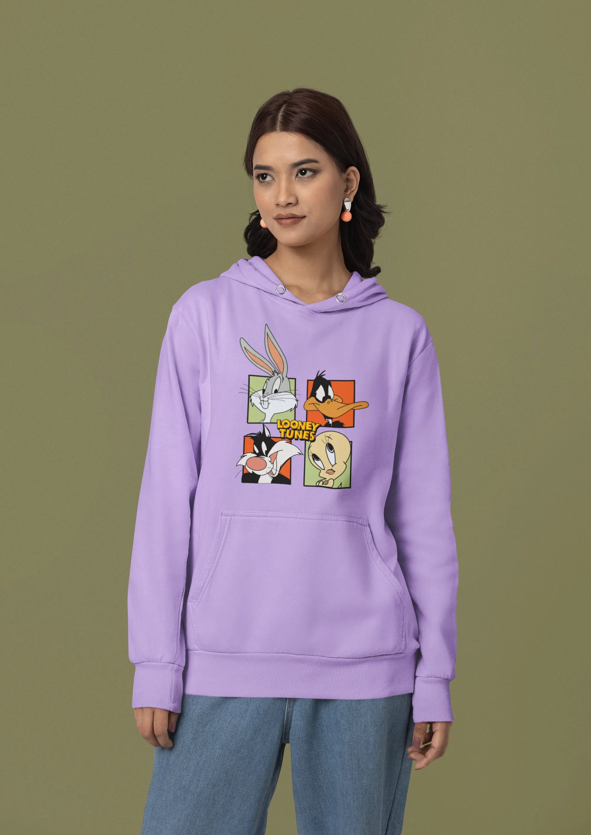 Second image of a female model wearing a lavender hoodie with a large Looney Tunes design. The illustration features portraits of several iconic Looney Tunes characters.