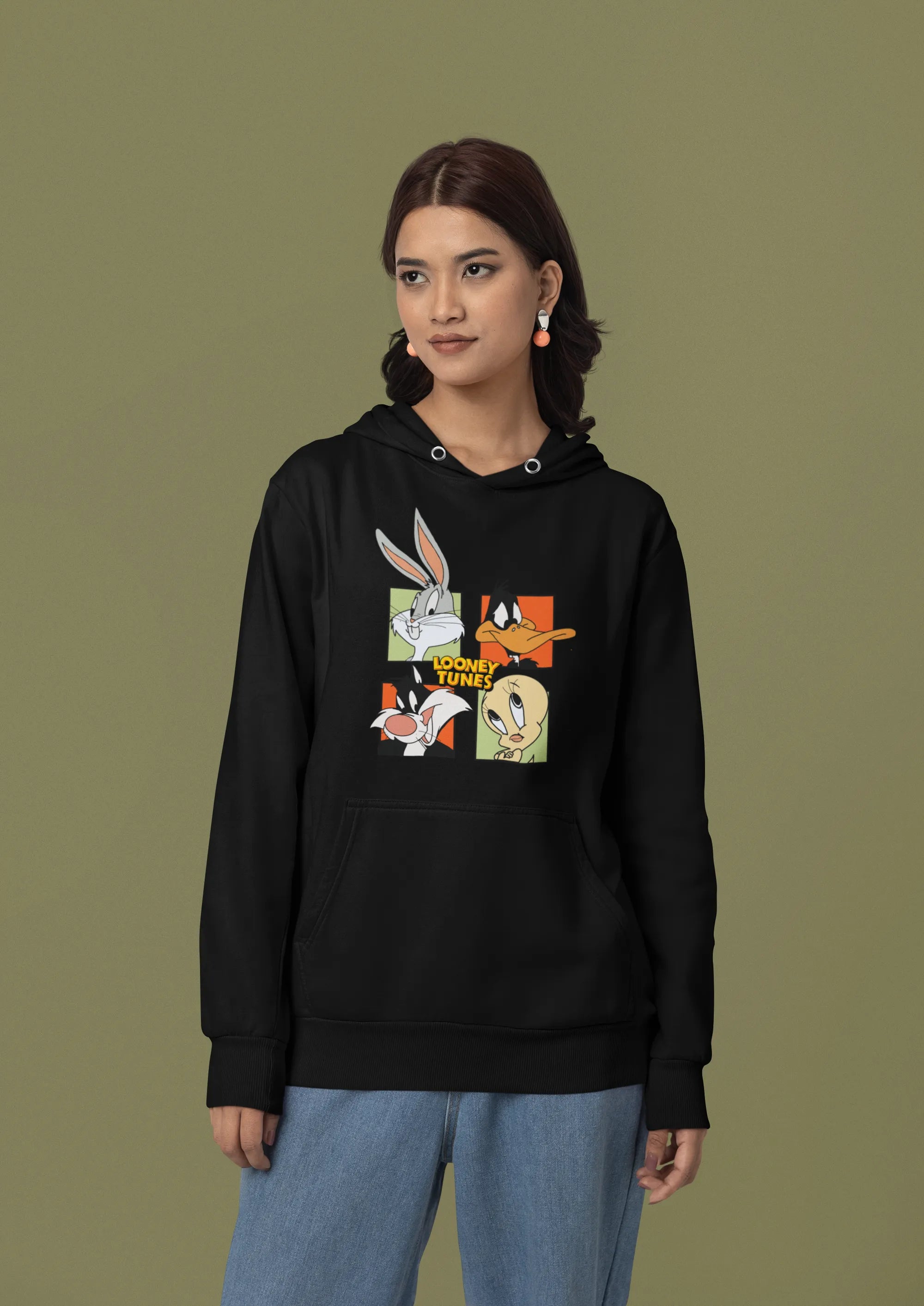 Second image of a female model wearing a black hoodie with a large Looney Tunes design. The illustration features portraits of several iconic Looney Tunes characters.