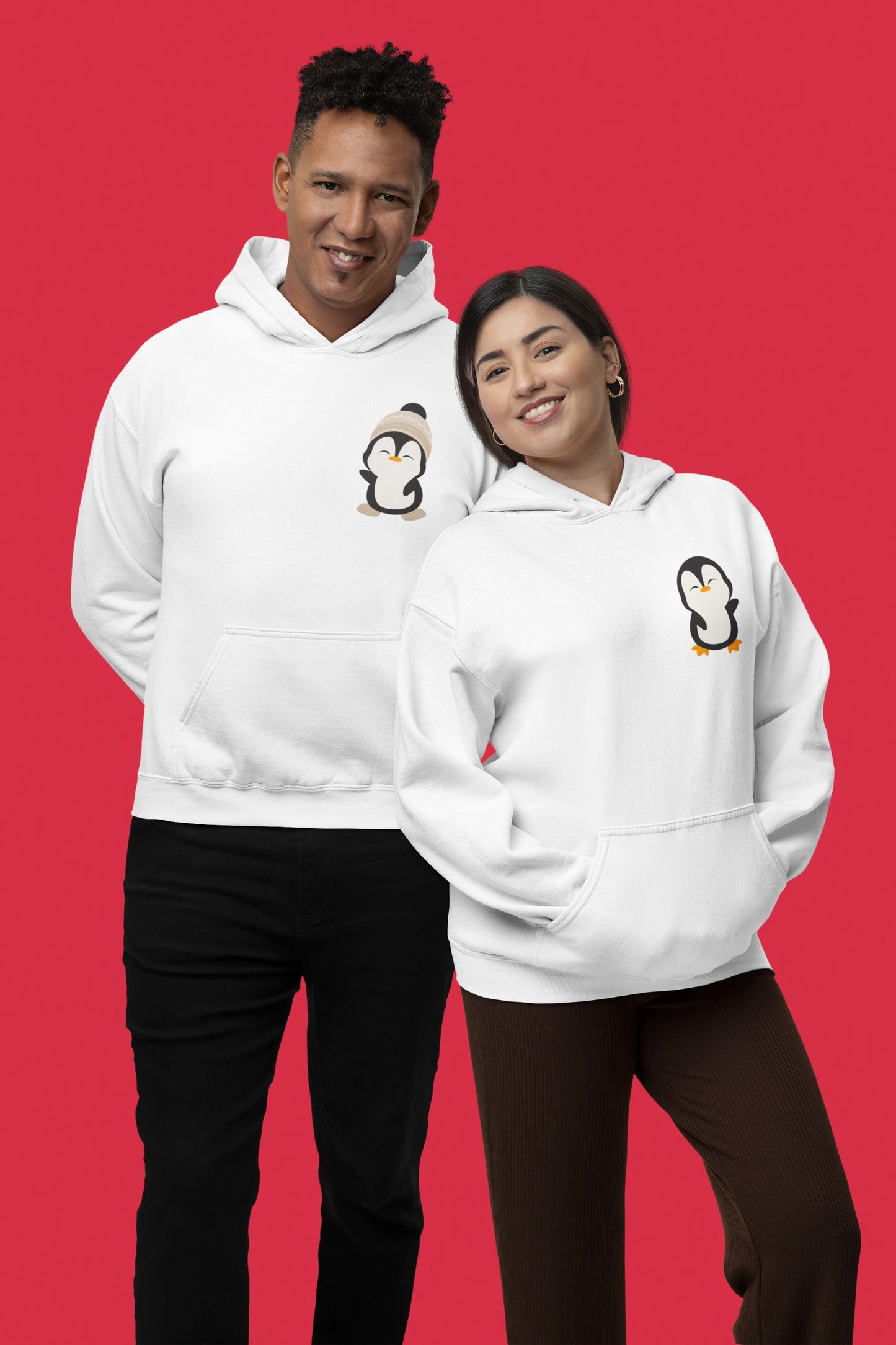 3rd front view of a couple wearing matching cream hoodies with a design of two penguins wearing woolen hats.