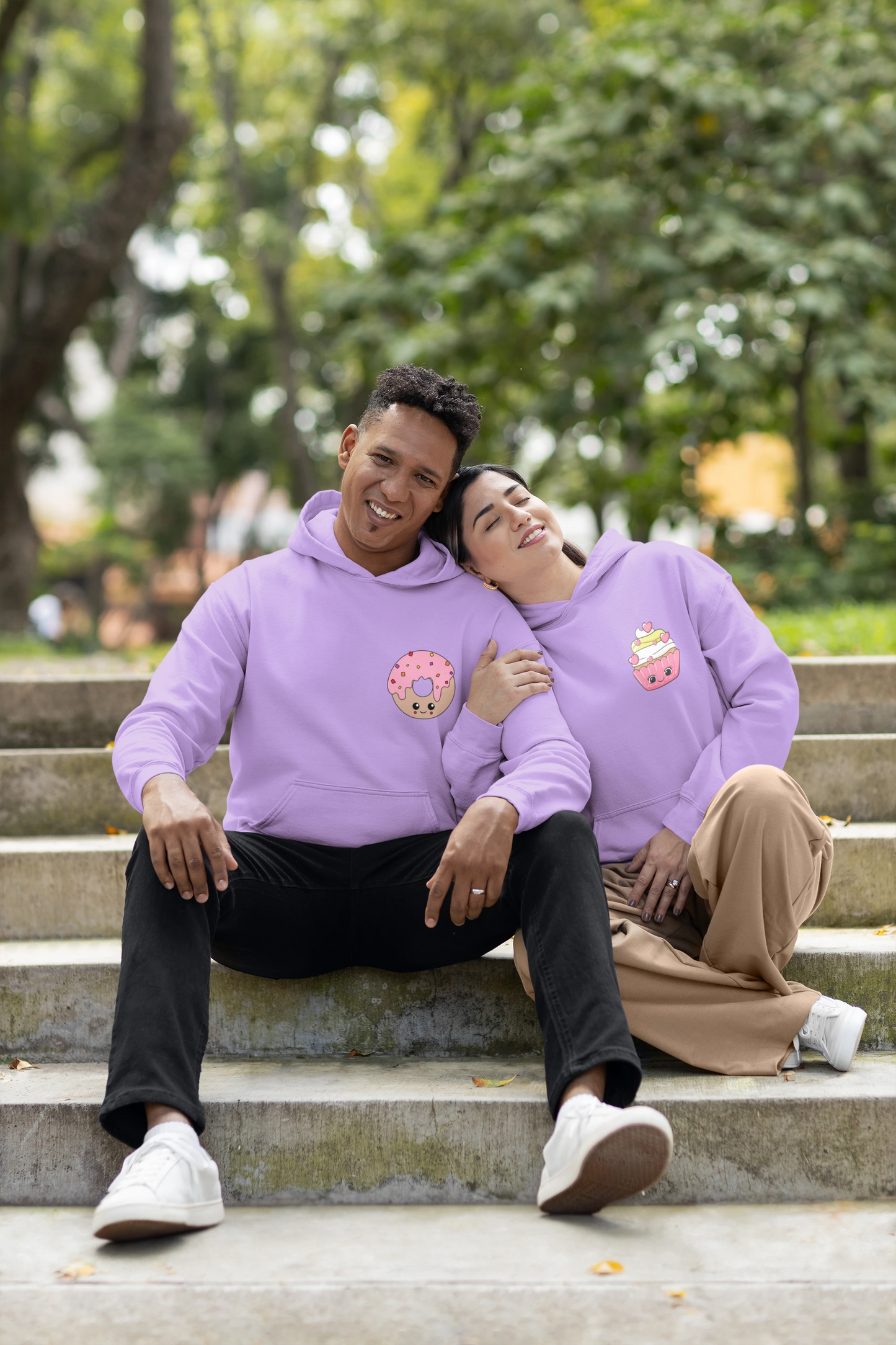 First front view of a couple wearing matching lavender hoodies, one with a animated donut and the other with a cupcake.