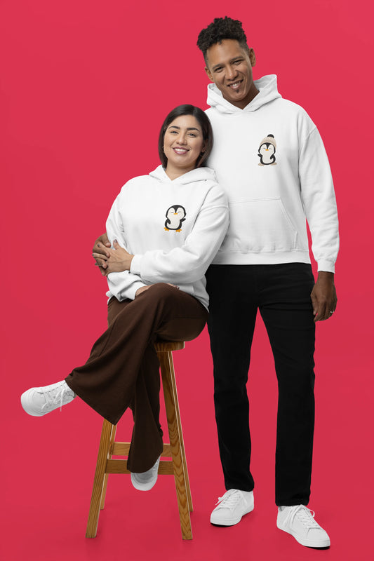 2nd front view of a couple wearing matching cream hoodies with a design of two penguins wearing woolen hats.